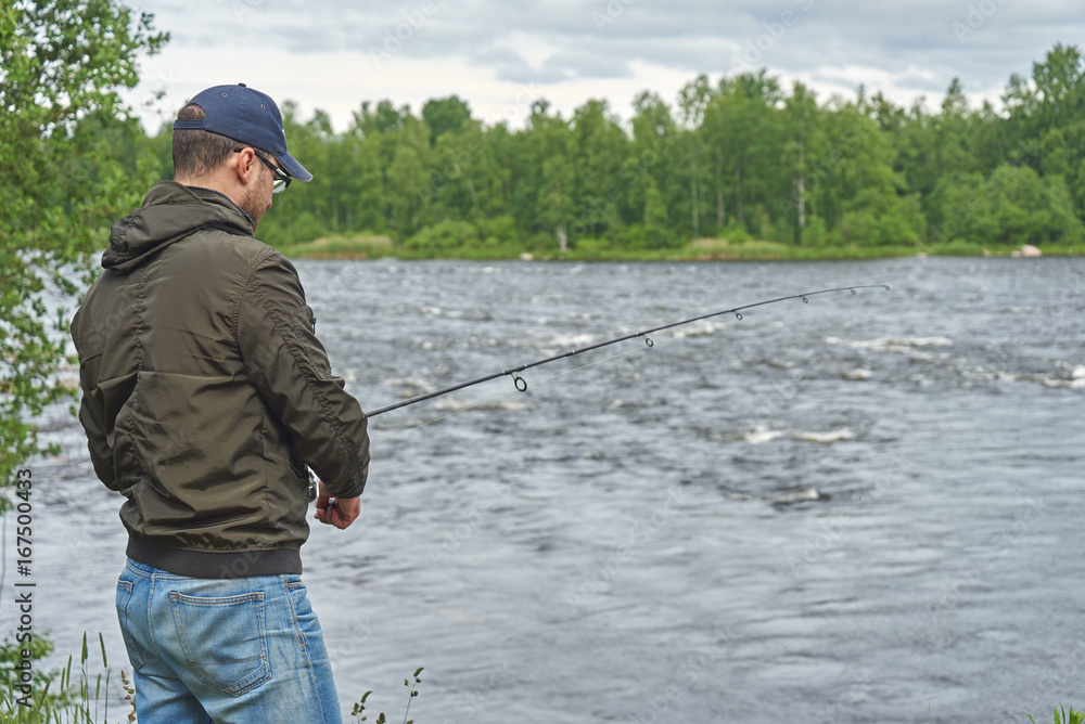 Man fishing with spinning rod in a rapid river. Man fishing with spinning rod in a rapid river.