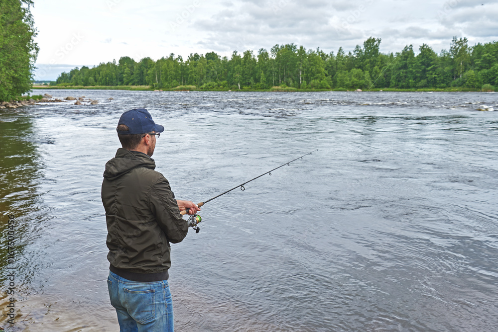 Man fishing with spinning rod in a rapid river. Man fishing with spinning rod in a rapid river.