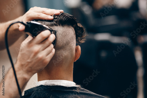 Barber shear hair electric car to a young guy hipper hair for a fashionable hairstyle. Concept hair salon, barbershop. photo