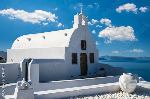 Oia Village, Santorini, Cyclade islands, Greece. Beautiful view of the town with white buildings, blue church's roofs and many coloured flowers.