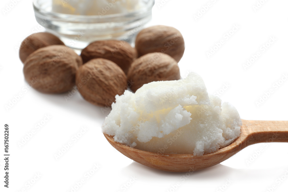 Shea butter in wooden spoon and nuts on white background
