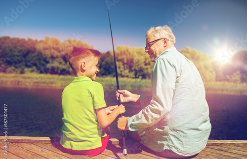 grandfather and grandson fishing on river berth