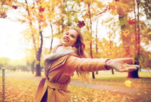 happy woman having fun with leaves in autumn park