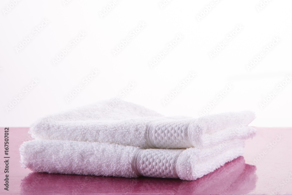 Spa. Two white towels on a pink marble table. White background. Spa. Two white towels on a pink marble table. White background.