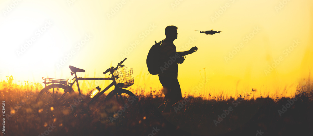 Young man operating of flying drone the setting sun