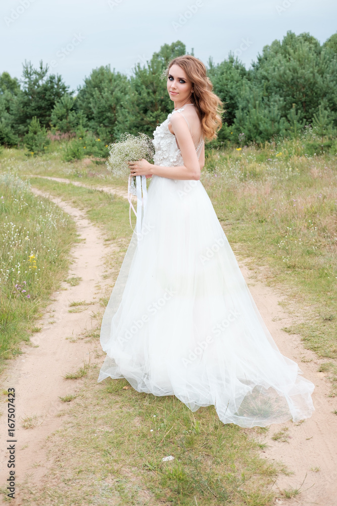 portrait of young pretty woman (bride) in white wedding dress outdoors, make up and hairstyle