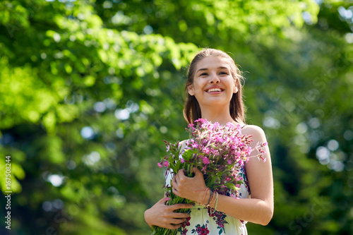 happy young woman with flowers in summer park
