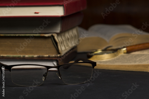 Books with glasses on black table and wooden background. High resolution image depicting reading/bokks industry..