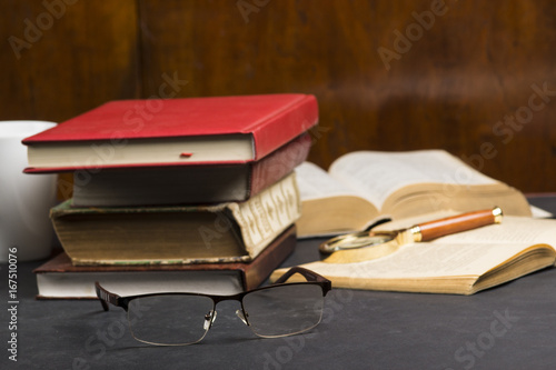 Books with glasses on black table and wooden background. High resolution image depicting reading/bokks industry.. photo