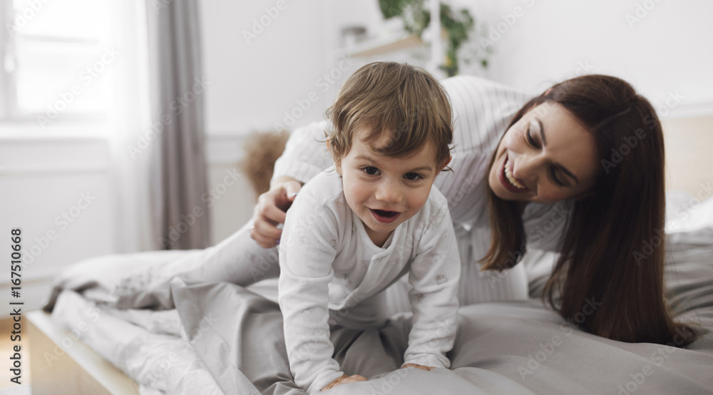 Portrait of playful baby boy with mother on bed at home Portrait of playful baby boy with mother on bed at home