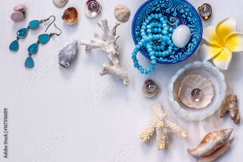 the white background on the marine theme with seashells, beads, corals, earrings, bracelet and a yellow flower