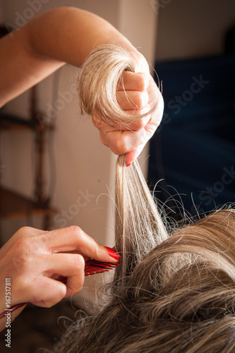 Parrucchiera che pettina e prepara i capelli lunghi biondi per l’acconciatura 