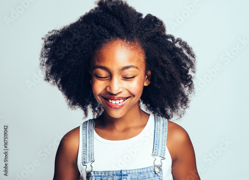 Smiling little African girl standing with her eyes closed