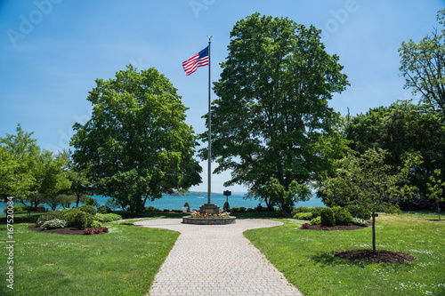 Tall flagpole with flag flying in lakeside park in summer