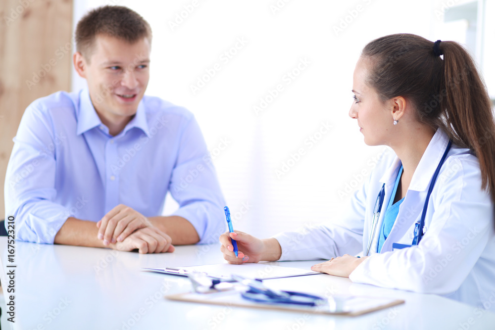 Doctor woman sitting with male patient at the desk Doctor woman sitting with male patient at the desk