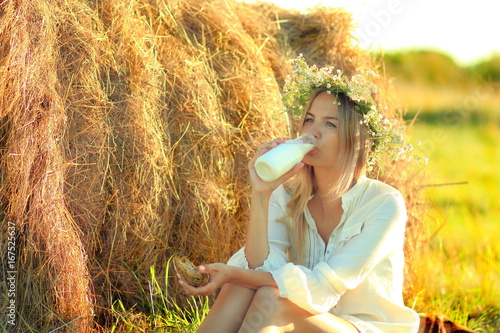 девушка у стога сена пьет молоко из бутылки