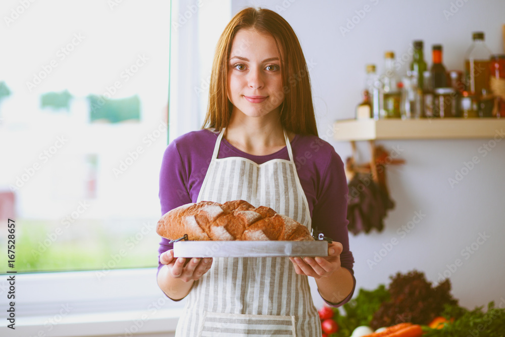 Young woman holding tasty fresh bread in her kitchen Young woman holding tasty fresh bread in her kitchen