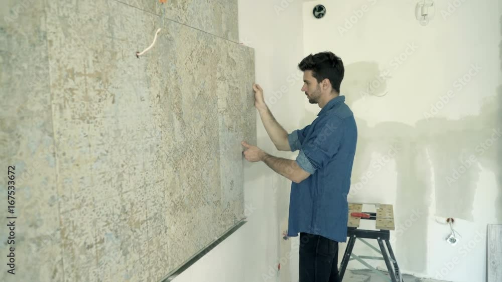 Unhappy man trying tiles on wall at his new home
Unhappy man trying tiles on wall at his new home