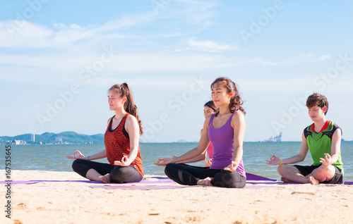 Yoga class at sea beach in sunny day ,Group of people doing lotus pose with clam relax emotion,Meditation pose,Wellness and Healthy balance lifestyle