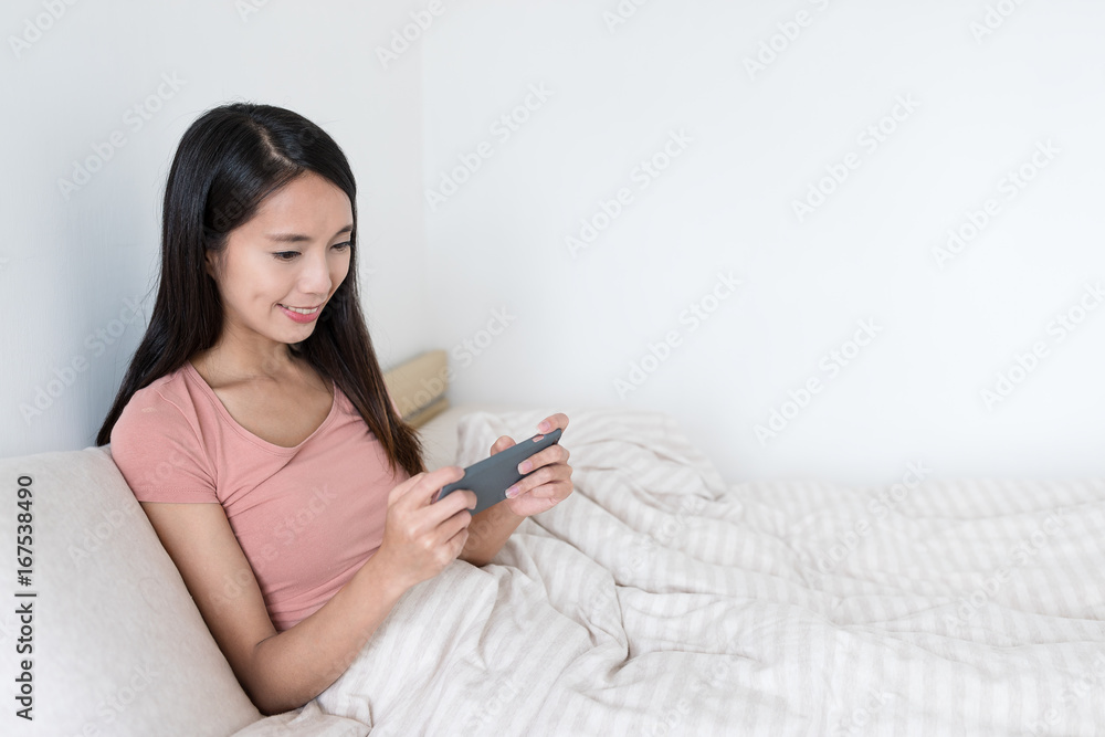 Woman playing game on cellphone inside bedroom Woman playing game on cellphone inside bedroom