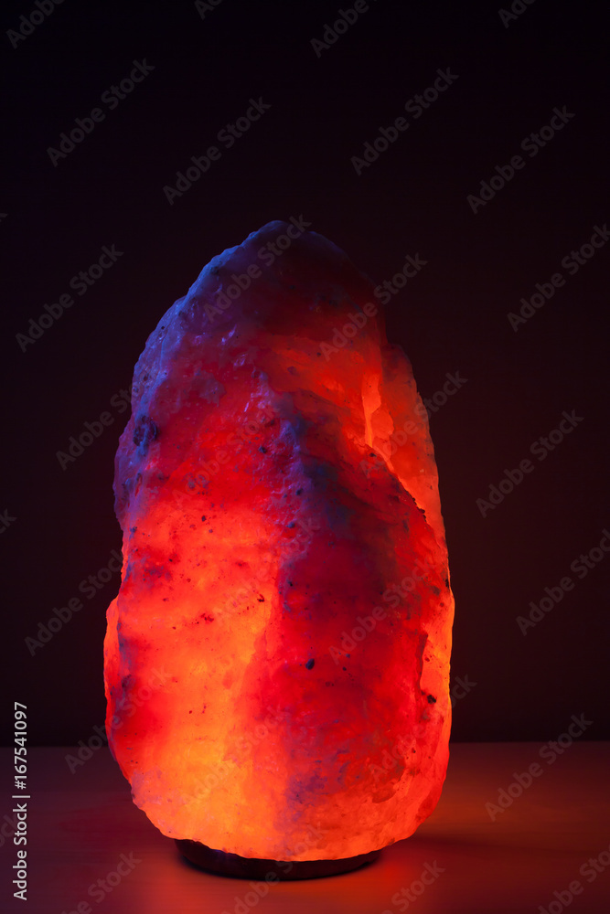 Illuminated himalayan salt lamp on wooden table Illuminated himalayan salt lamp on wooden table