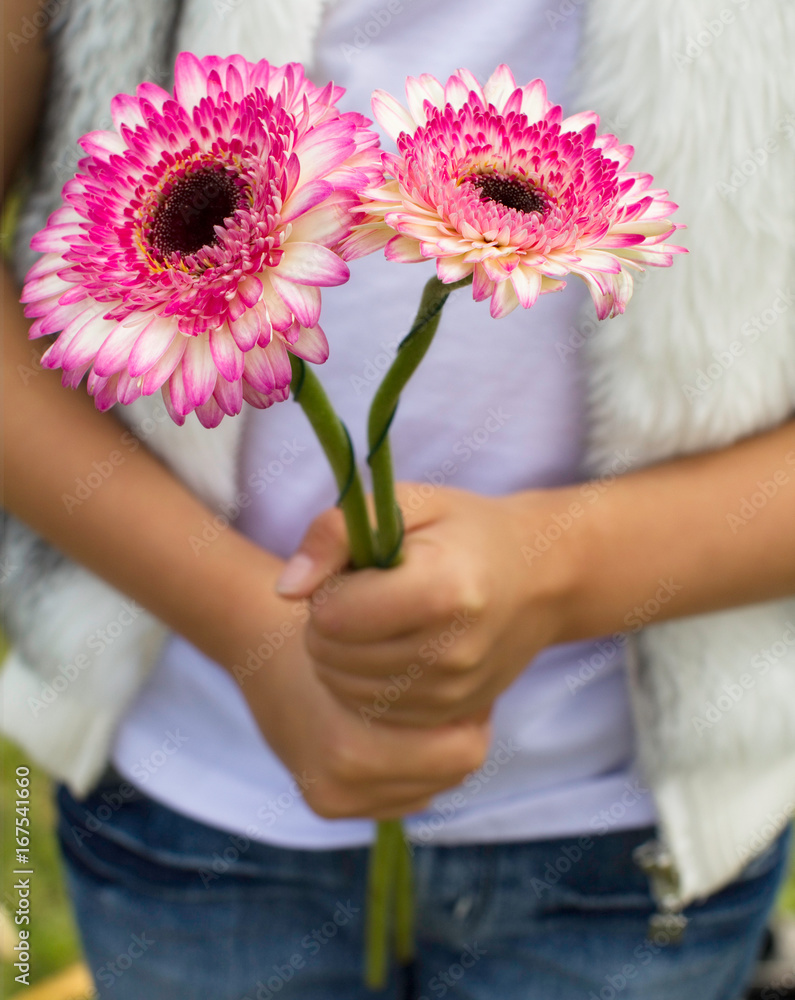 Young girls hands holding pick and white flowers
