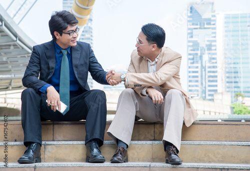 two businessmen shaking hands in city background, business success concept.