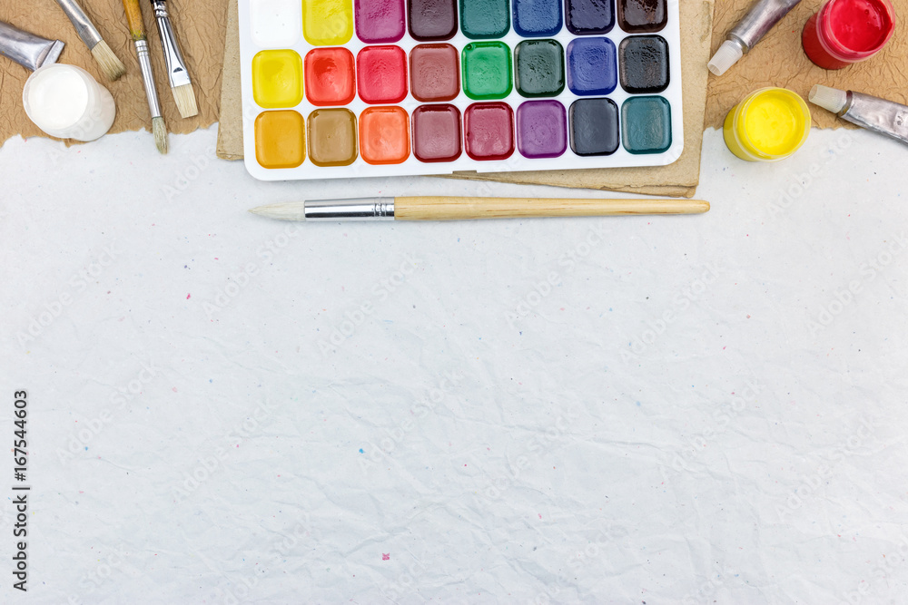 Fototapeta premium watercolor paints palette with paintbrushes on gray recycled paper background