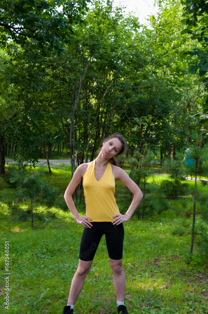 Girl engaged fitness in the park, exercise head tilts Girl engaged fitness in the park, exercise head tilts