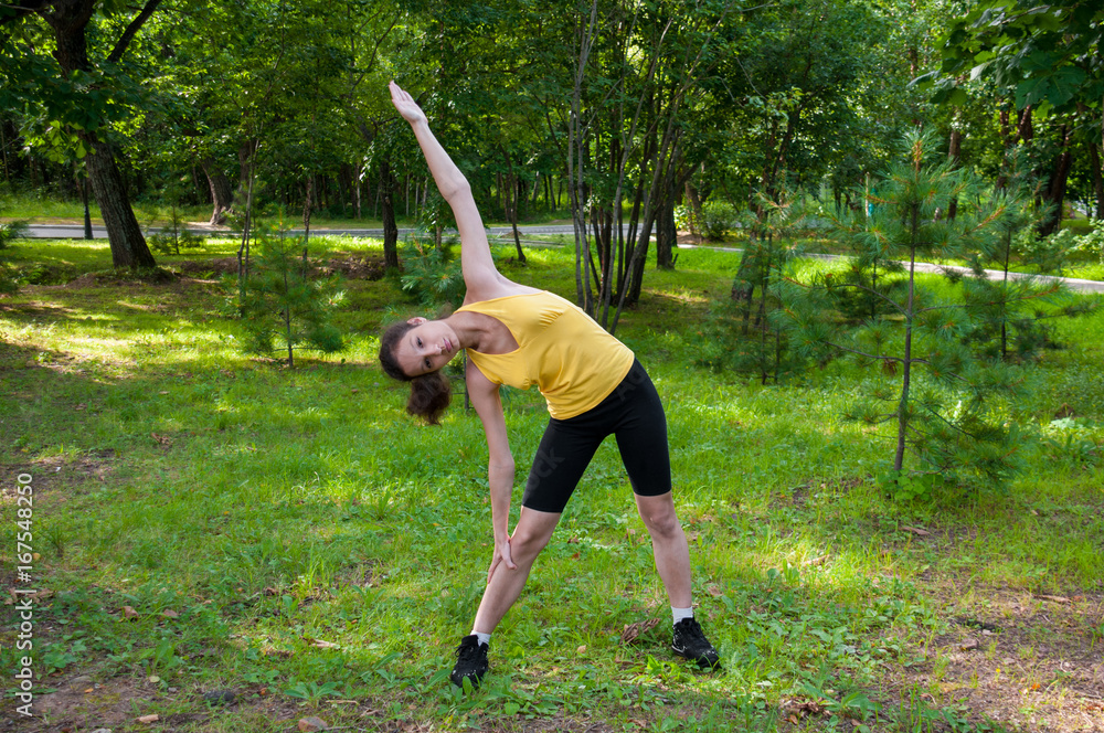 Girl is engaged fitness in park, exercise slopes to side Girl is engaged fitness in park, exercise slopes to side