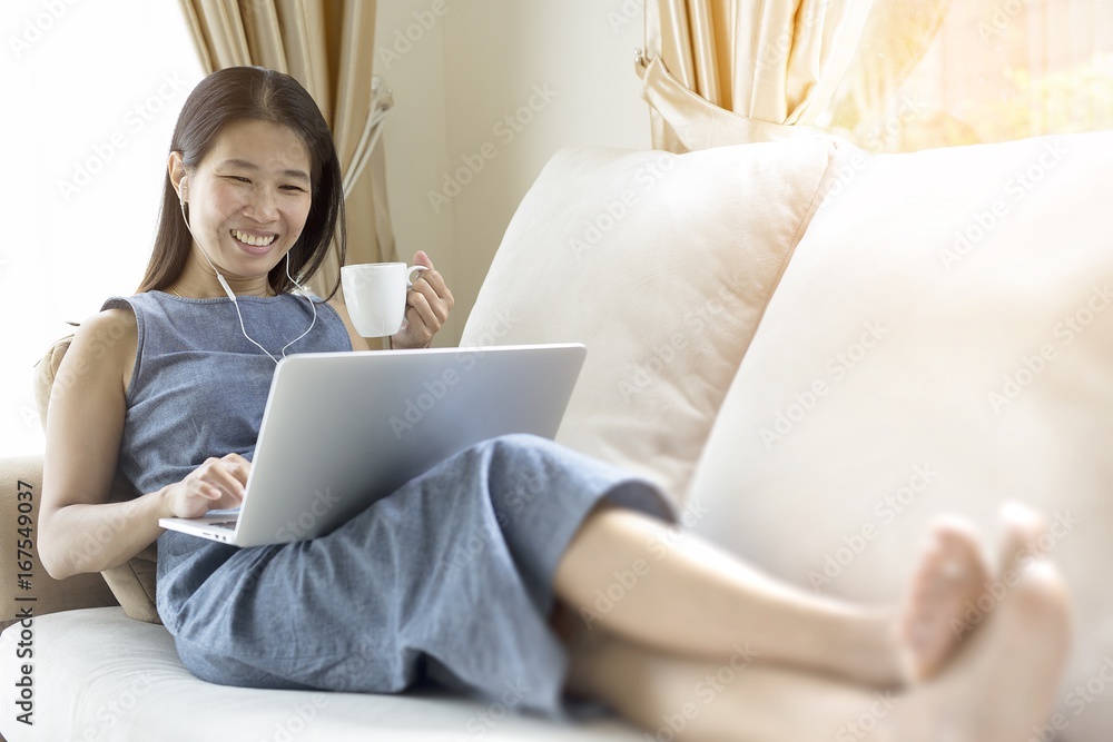 Working woman sitting on the sofa. She is working with a notebook and is drinking coffee. The concept of women working with technology. Working woman sitting on the sofa. She is working with a notebook and is drinking coffee. The concept of women working with technology.
