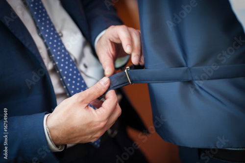 Mani maschili che regolano la fibbia del cinturino del gilet dello sposo