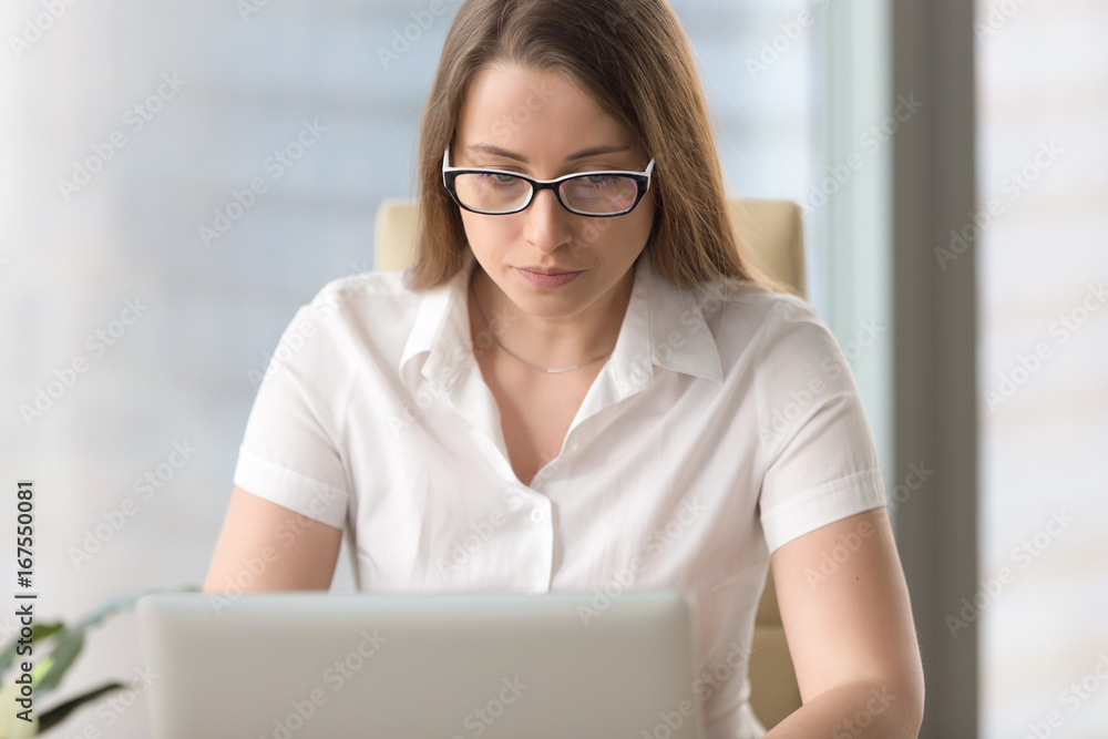 Serious worried businesswoman in glasses working on laptop, using computer, having problem error on pc, looking at screen, focused on work online, browsing internet, antivirus protection, head shot Serious worried businesswoman in glasses working on laptop, using computer, having problem error on pc, looking at screen, focused on work online, browsing internet, antivirus protection, head shot
