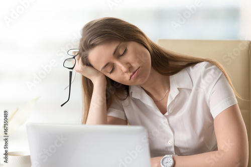 Bored sleepy businesswoman sitting half asleep at workplace, lazy woman disinterested in boring routine, tired employee dozing on hand during break, falling asleep at desk, lack of sleep, head shot