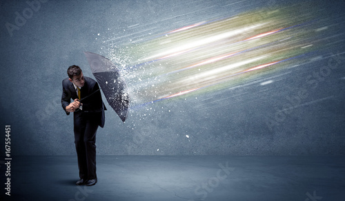 Business man defending light beams with umbrella concept