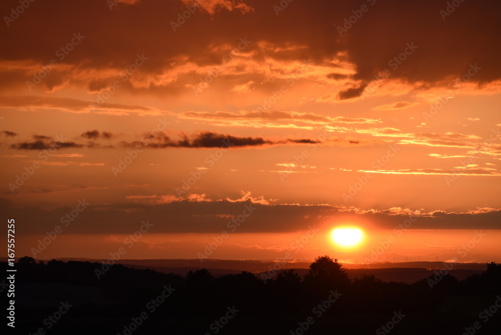 Sonnenuntergang mit kräftigenund intensiven Abendrot mit Windrädern im Hintergrund