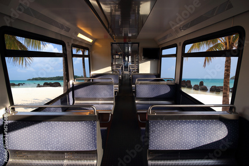 Empty interior of the train for long and short distance in Europe train carriage  and tropical blue sea over window. © sittinan