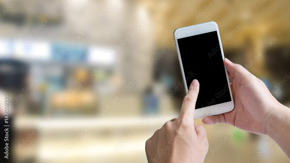 Hand using empty screen of smartphone for present application on shopping mall background 16:9 size.