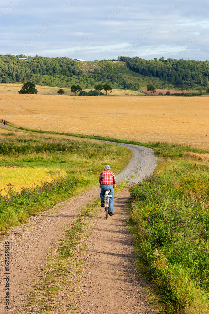 Man cycling on a gravel road in a rural landscape Man cycling on a gravel road in a rural landscape
