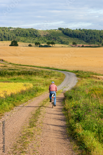 Man cycling on a gravel road in a rural landscape