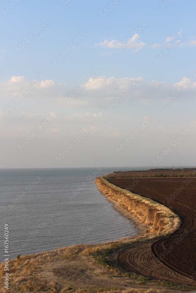 Plowed field is located near the cliff near the sea