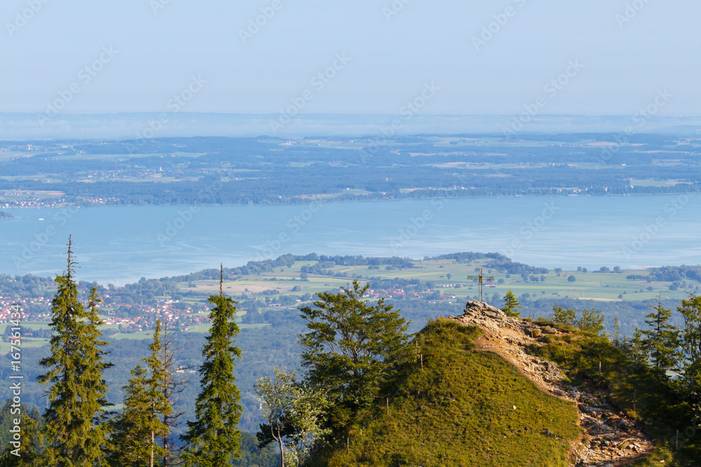 Obraz premium Kleiner Gipfel mit Gipfelkreuz auf dem weg zum Hochfelln mit Chiemsee im Hintergrund