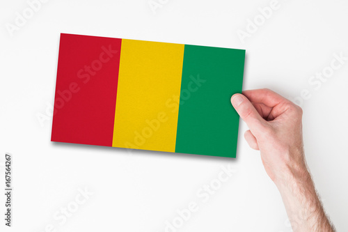 Male hand holding guinea flag