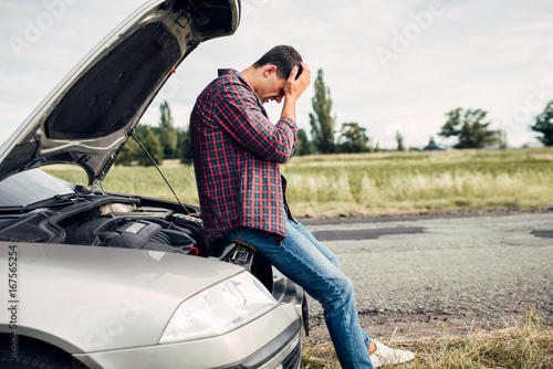 Tapeta Depressed man sitting on a hood of broken car