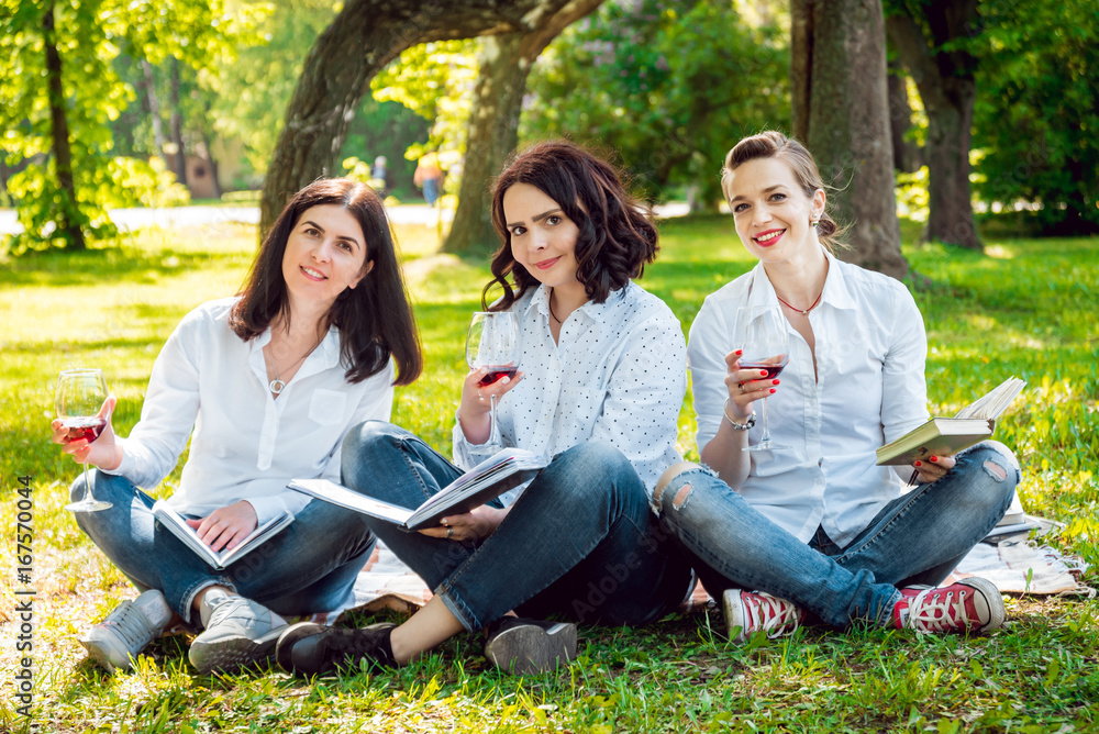Young beautiful girls with glass of red wine and books in the park. Young beautiful girls with glass of red wine and books in the park.