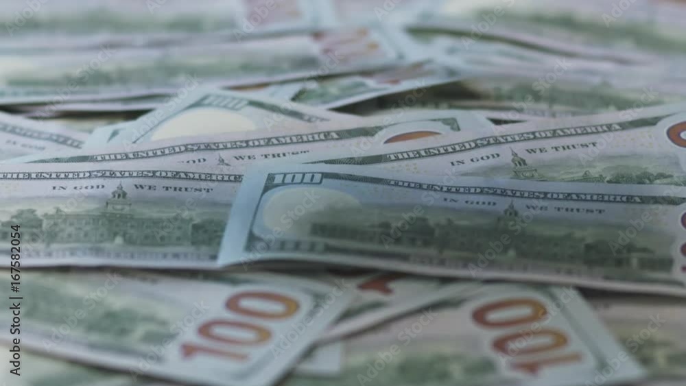 Slow motion hundred dollar bills falling on table Slow motion hundred dollar bills falling on table