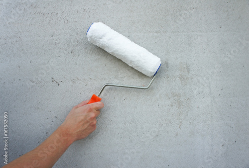 Paint roller in hand, grey wall background
