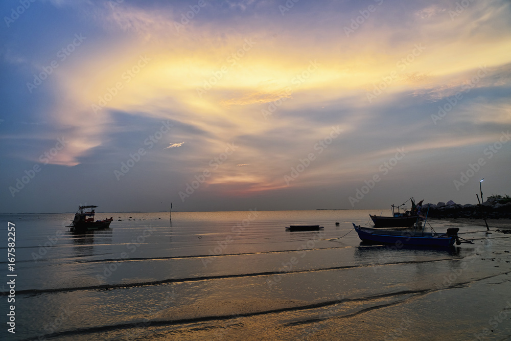 Many fishing boat on pebble beach and twilight