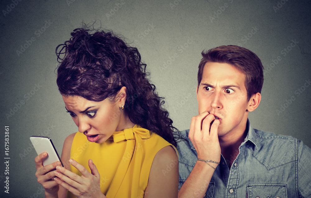Cheating On Boyfriend While On Phone Foto de Cheating boyfriend. Man nervously biting fingernails while shocked girlfriend reading text messages on his mobile phone do Stock | Adobe Stock