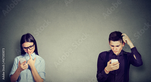 Perplexed man and woman looking at mobile phone photo